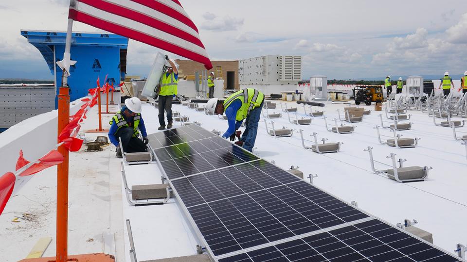 太阳能电池板安装工人在建筑物的屋顶上工作